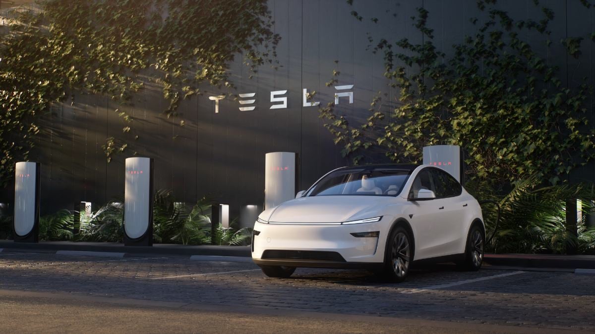 White 2026 Tesla Model Y Juniper estacionado en una estación de carga, diseño pulido con una pared moderna de Tesla y saliva a la luz de la tarde suave